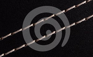 White thread stitching on black leather.