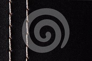 White thread stitching on black leather.