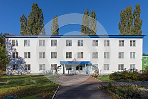 White three-storey building in the park.