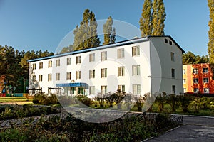 White three-storey building in the park.