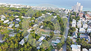 White three-story vacations homes, condo buildings surrounding by lush green trees in beach neighborhood along county road 30A,