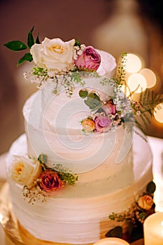 White three tiered wedding cake. White creamy cake decorated with fesh fruits, berries and flowers.