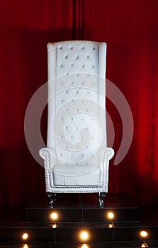 White throne on a red background, chair with high back, elevated position