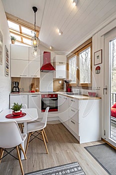 White tiny modern kitchen with red components, reconstruction, cosy small panel house in Prague, Czech Republic