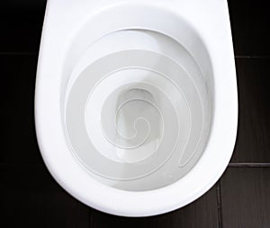 White toilet bowl in the bathroom, and flushing the water.