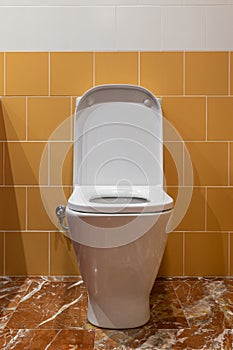 White toilet with yellow tiles, marble flooring, rectangle toilet seat and opened lid