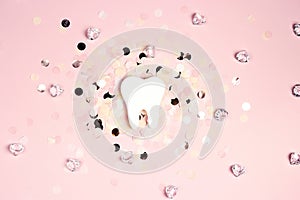 White tooth on a pink background with confetti and crystals