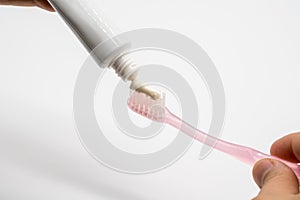 White toothpaste squeezed on pink toothbrush