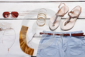 White top with blue shorts and bracelets.