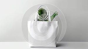 A white tote bag, accented with vibrant green leaves, stands against a grey backdrop