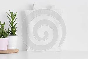 White tote bag mockup with succulents on a white table
