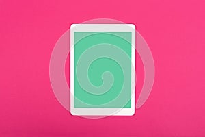 White touchpad with blank green screen on magenta background. Flat lay