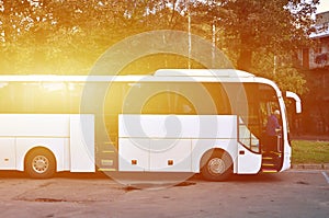 White tourist bus for excursions. The bus is parked in a parking lot near the park