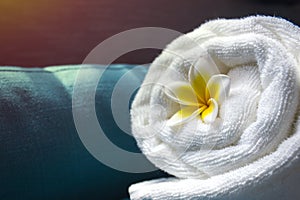 White towel and a flower of Frangipana on a dark background. The concept of SPA.