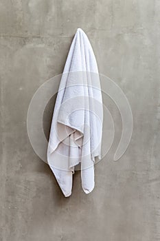 White towel is hanging on the exposed concrete wall in the bathroom.