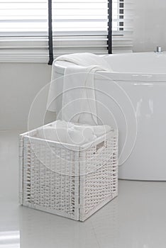 White towel in wooden basket with modern bath tub