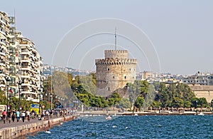 White Tower and unidentified people are walking on the embankment in Thessaloniki, Greece