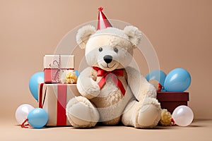 white toy bear in birthday hat with gift box and balloons on beige background with copy space