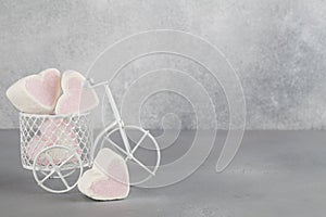 White toy bike carrying candy in form of hearts. Valentines day minimalism background