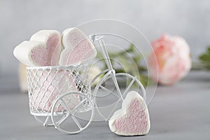 White toy bike carrying candy in form of hearts. Valentines day minimalism background