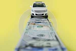 White toy car on money road on yellow background