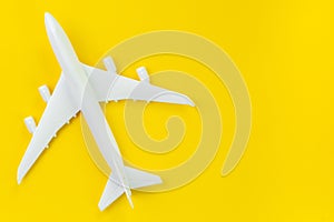 White toy commercial airplane on solid yellow background using as travel and transportation business wallpaper