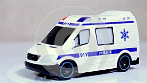 White toy police bus scale model car rotating on white background.
