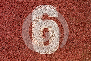 White track number on red rubber racetrack, texture of running racetracks in small outdoor stadium