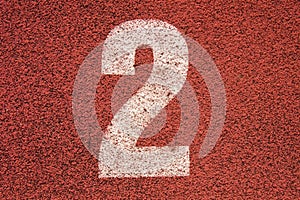 White track number on red rubber racetrack, texture of running racetracks in small outdoor stadium