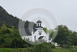 Church with bell tower in a lush green landscape of grass and forest