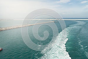 White trail, foam and waves on the Mediterranean sea behind the liner sailing from the port of Valencia, view of the port,