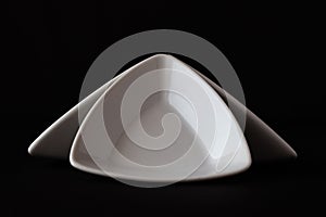 White triangular ceramic bowls with on the black background.