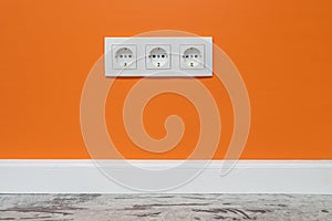 White triple outlet on orange wall