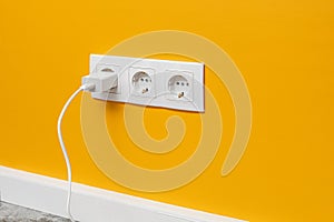 White triple outlet on yellow wall