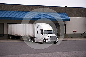 White truck with a trailer in a warehouse on the unloading