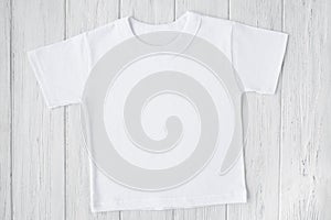 White tshirt mockup on wooden table background. Template, flat lay. Kid, child clothes