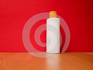 White tube bottle of shampoo, conditioner, mouthwash, on a red background