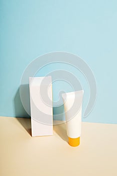 White tube and box of sunscreen on blue background. Sun Protection. Copy space