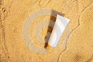 White tube of sunscreen on beach sand. Sun Protection. Top view. Copy space