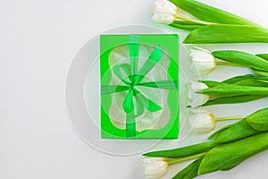 White tulip flowers and black gift box on light background flat lay. Bouquet greeting card. Website banner top view