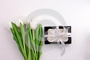 White tulip flowers and black gift box on light background flat lay. Place for text 8 March Happy Womens Mothers Day