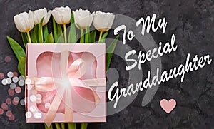 White tulip flowers and pink gift box dark background flat lay. To My special Granddaughter card sign text. I Love you