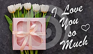 White tulip flowers and pink gift box on dark background flatlay.I Love You So Much card sign text.Flower Bouquet banner