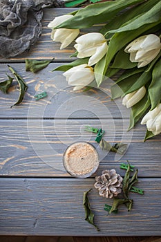 White tulips and candles on a blue wooden background. Top view with copy space