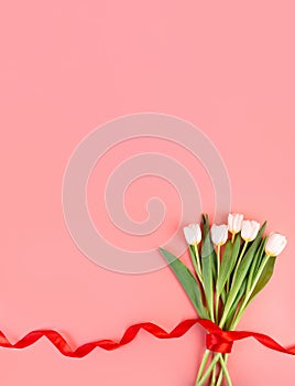 White tulips flowers, flatlay. Beautiful bouquet of tulips on stem with leaves isolated on pastel pink background. NaturÐµ object