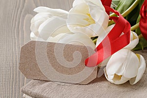 White tulips on wood table with paper tag