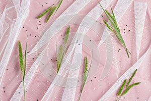 White tulle and beautiful wilds grass on a pink background. feminine wedding, birthday floral concept. top view