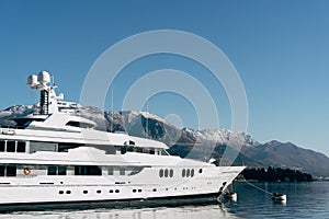 White two-deck yacht moored at the pier with mountains in the background