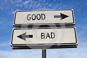 White two street signs with arrow on metal pole with word good and bad