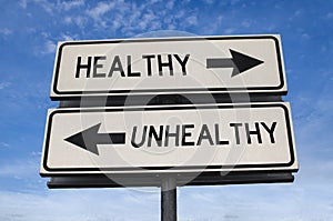 White two street signs with arrow on metal pole with word healthy and unhealthy